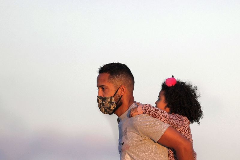 A child gets a piggy back ride from her father as the sun begins to set in Cruzeiro Square in Brasilia, Brazil. (Photo by Eraldo Peres/AP Photo)